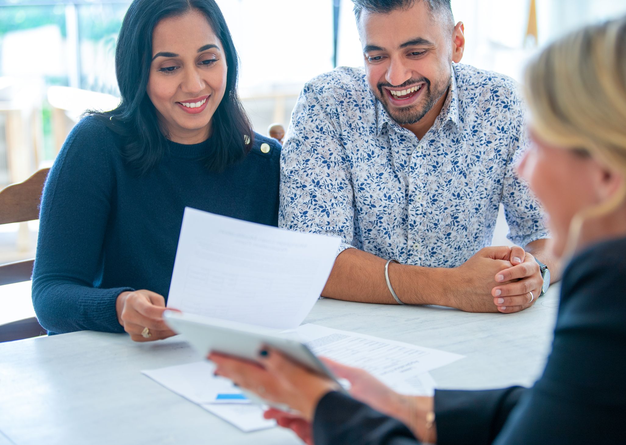 Olivia Wann Law Office, Legal Services.  A couple meeting with financial advisor for business planning They are sitting at a table at a paper work document a digital tablet presentation.