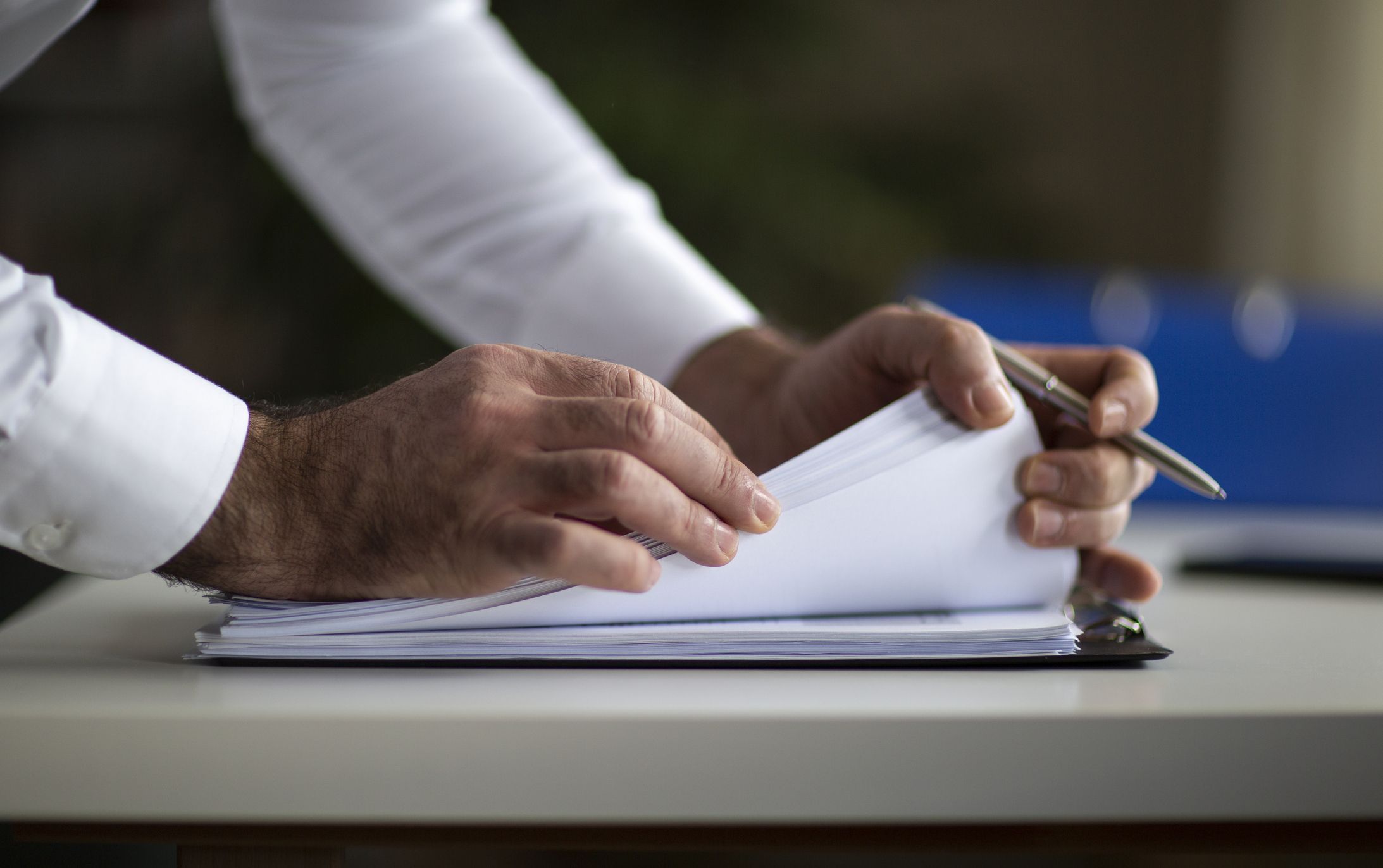 Male arm in suit offer insurance form clipped to pad