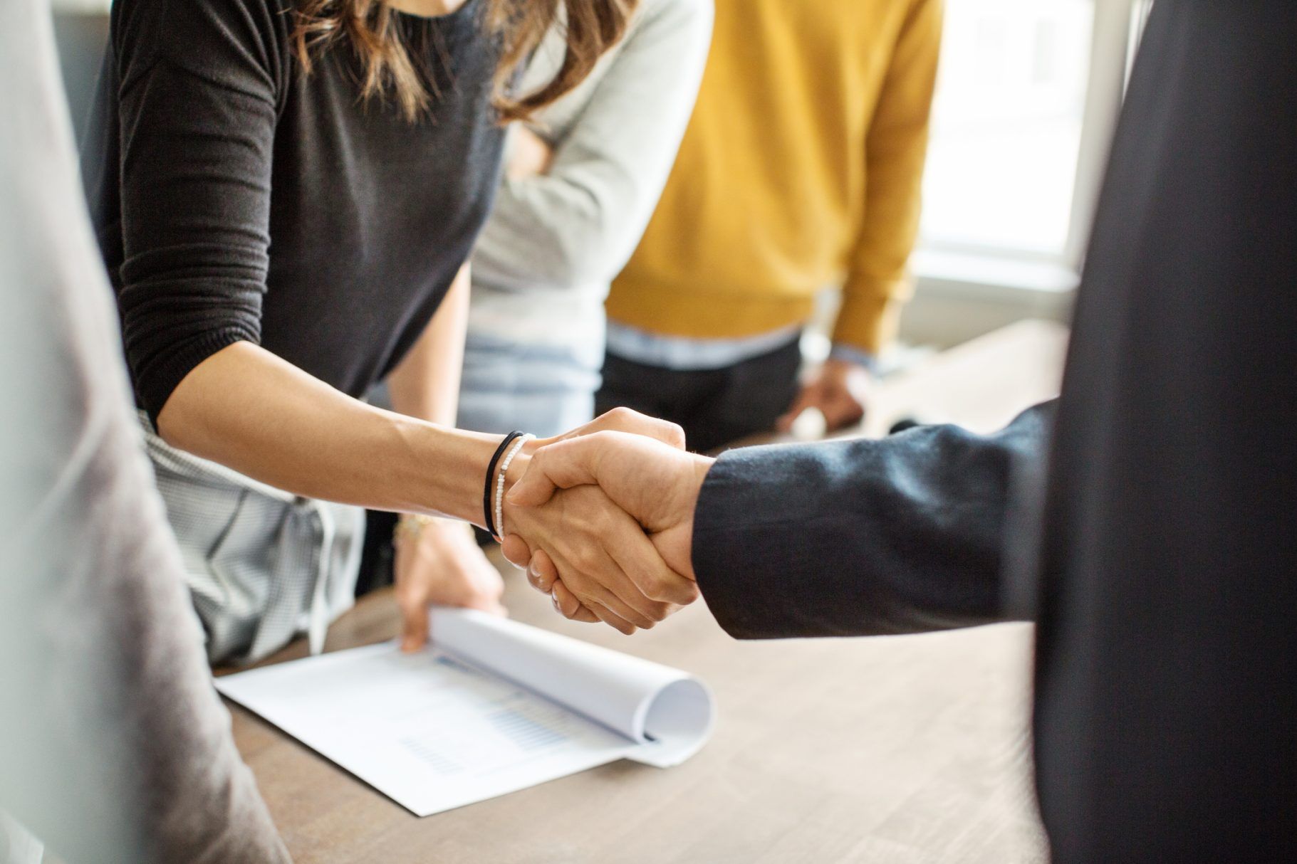 Cropped shot of businessman greeting a young professional around the table in office. Close up of business people shaking hands in office.