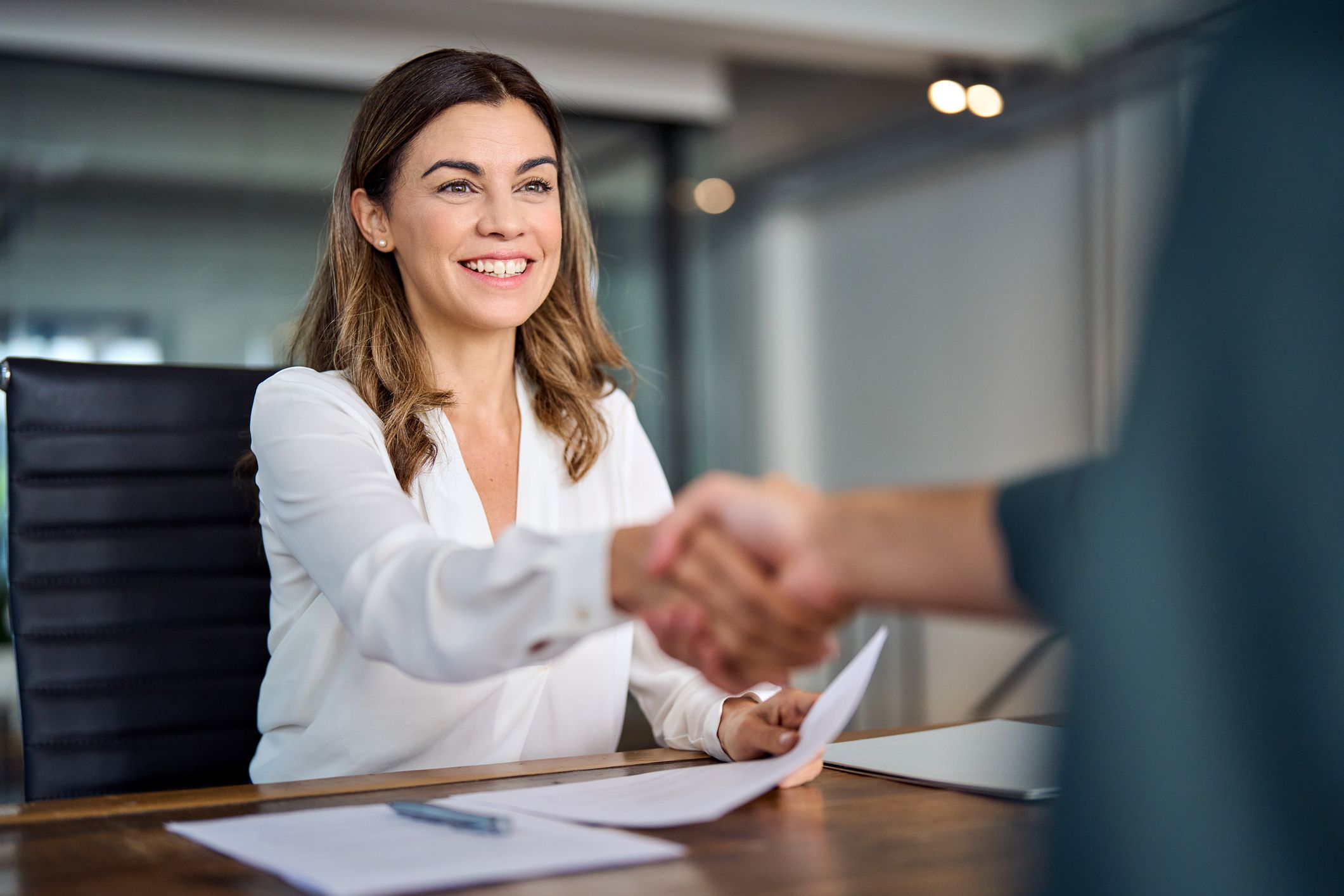 Happy mid aged business woman manager handshaking with employee